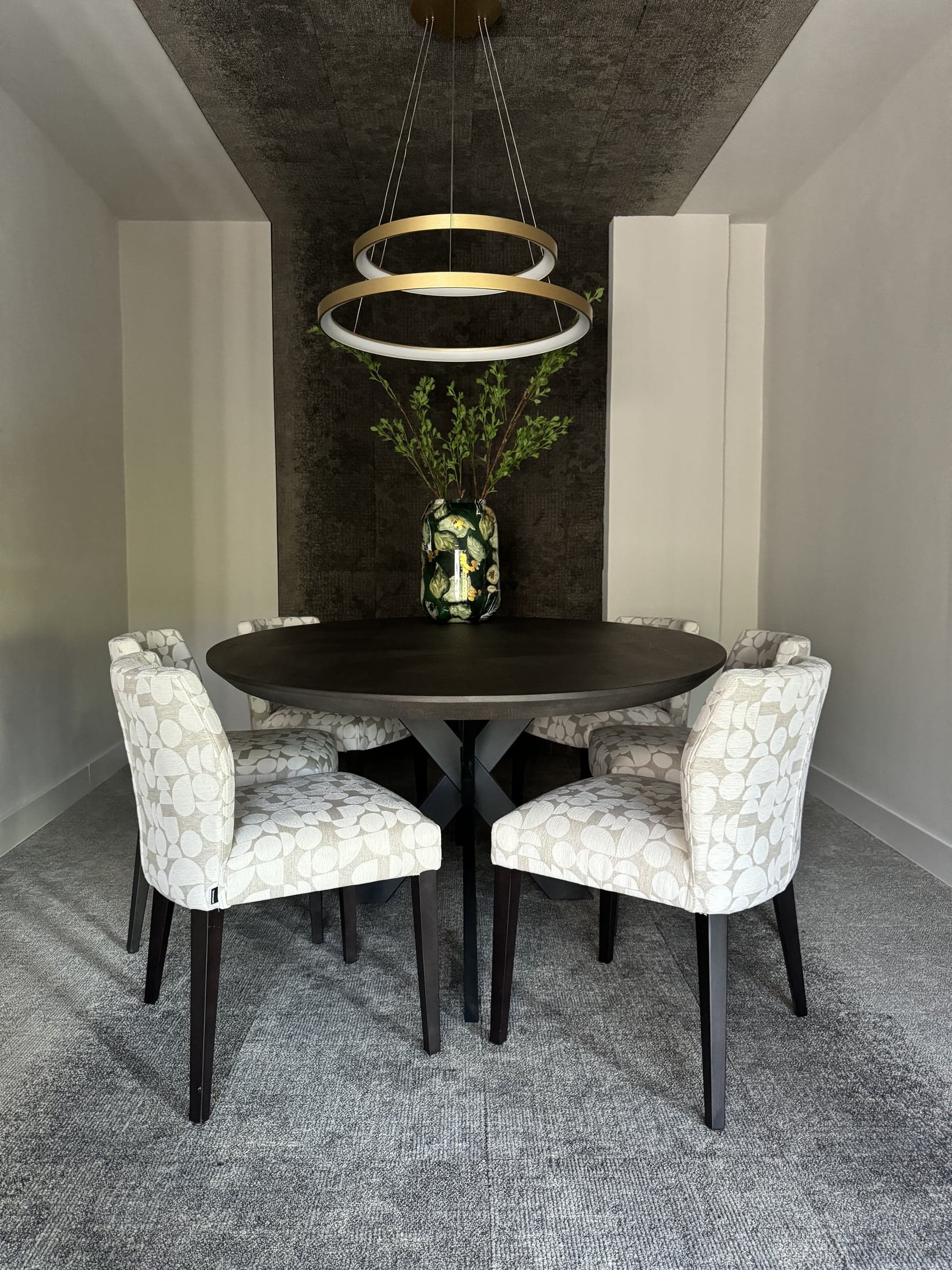Vergaderhoek met een ronde tafel, gestoffeerde stoelen en een ringvormige hanglamp in een accountantskantoor in Oisterwijk