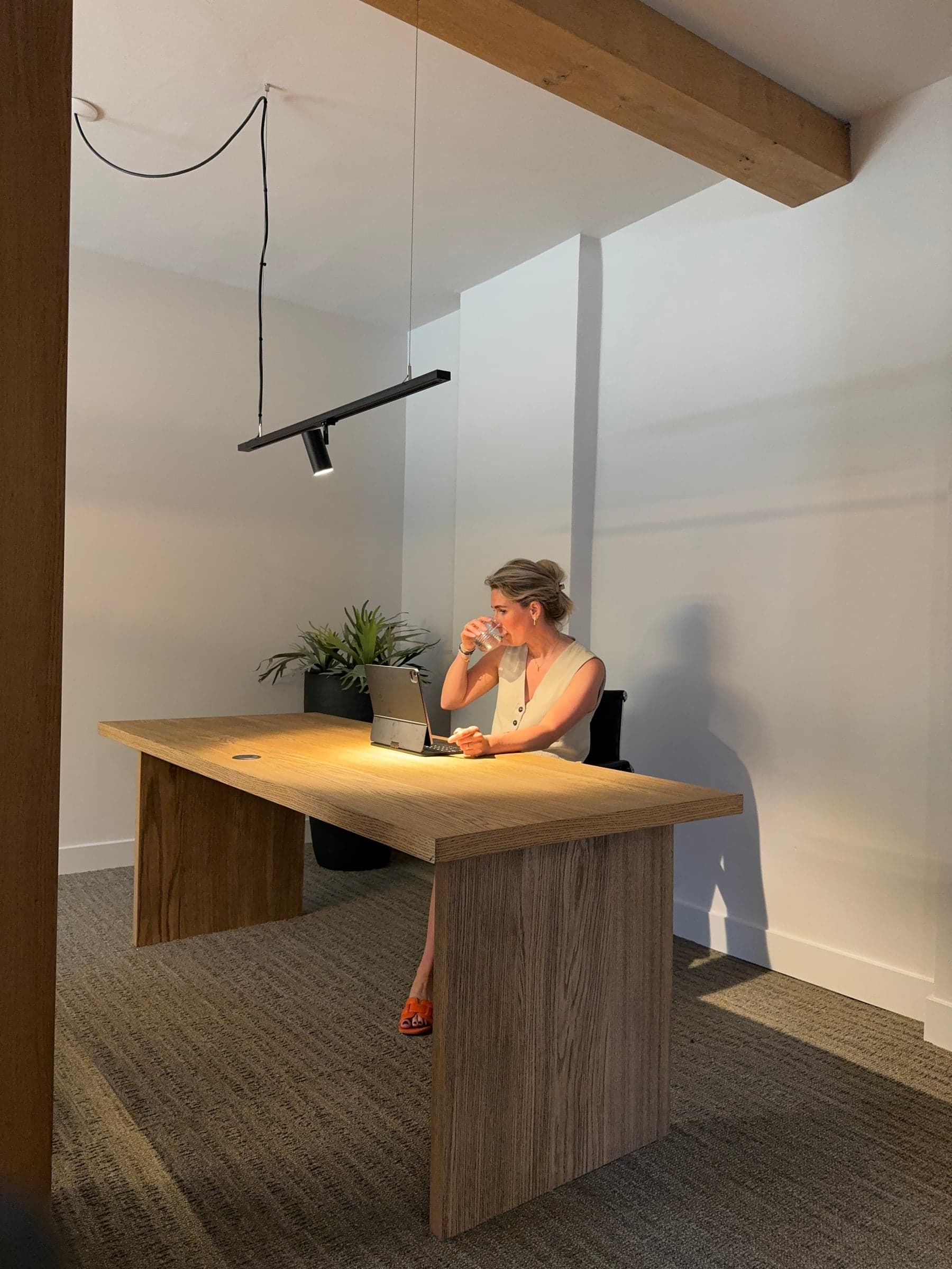 Werkplek met een houten bureau op maat bij een glazen scheidingswand in een accountantskantoor in Oisterwijk