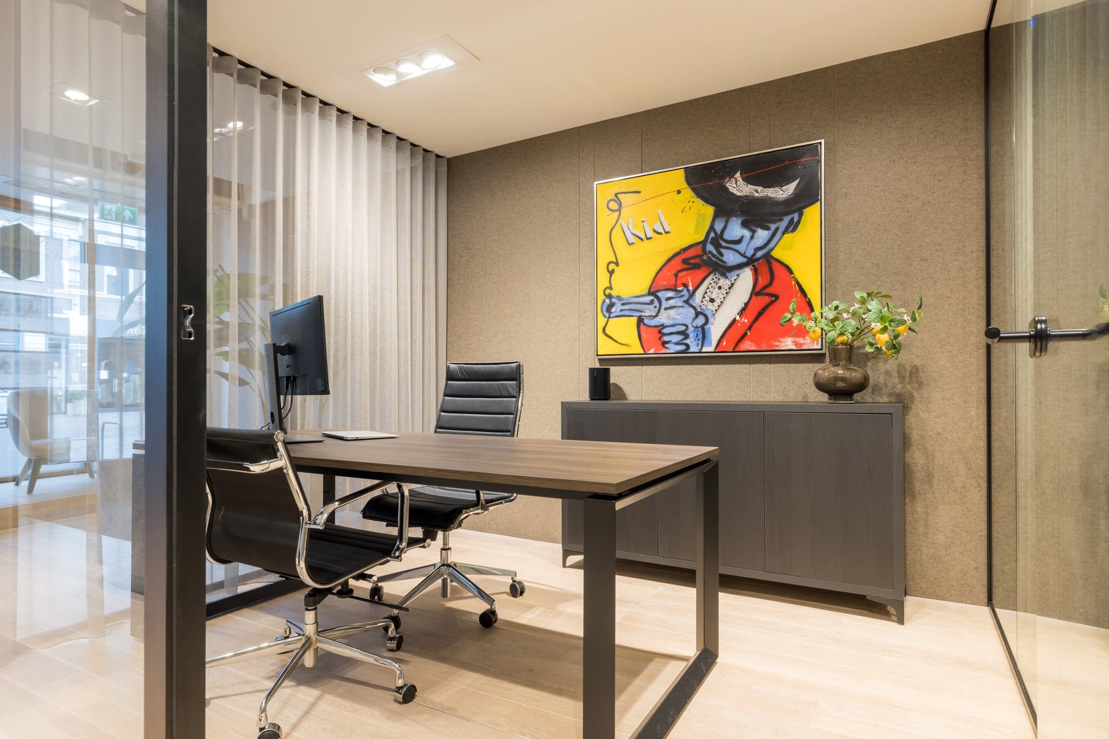 Werkkamer met een bureau en een kleurrijk kunstwerk aan de wand in een makelaarskantoor in Oisterwijk