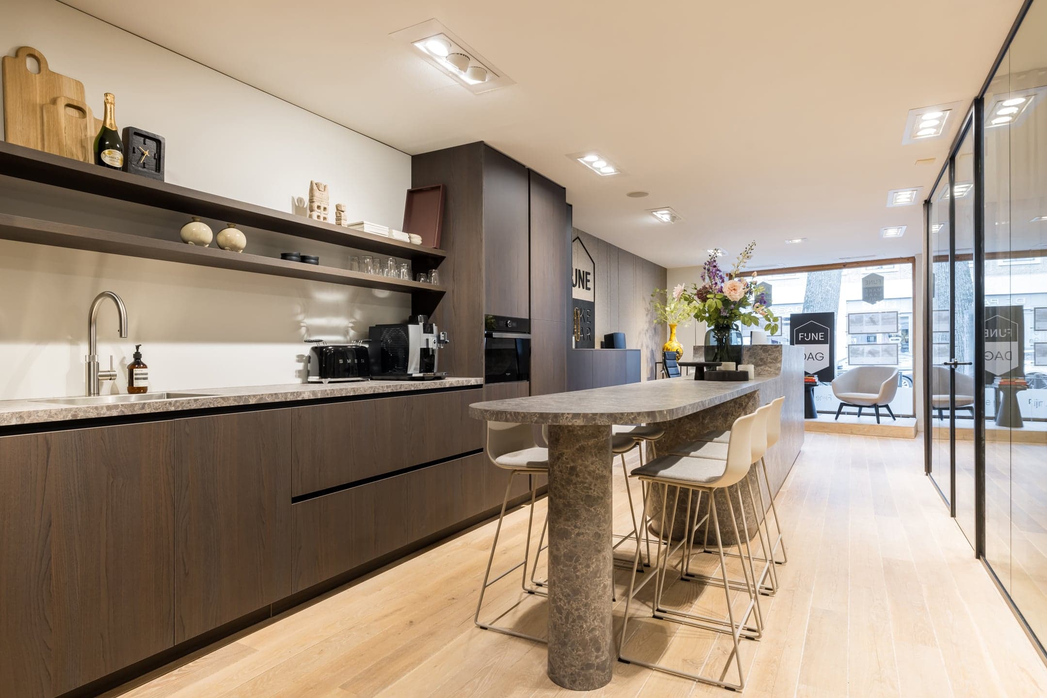 Pantry met een natuurstenen bar, barkrukken en open schappen in een makelaarskantoor in Oisterwijk