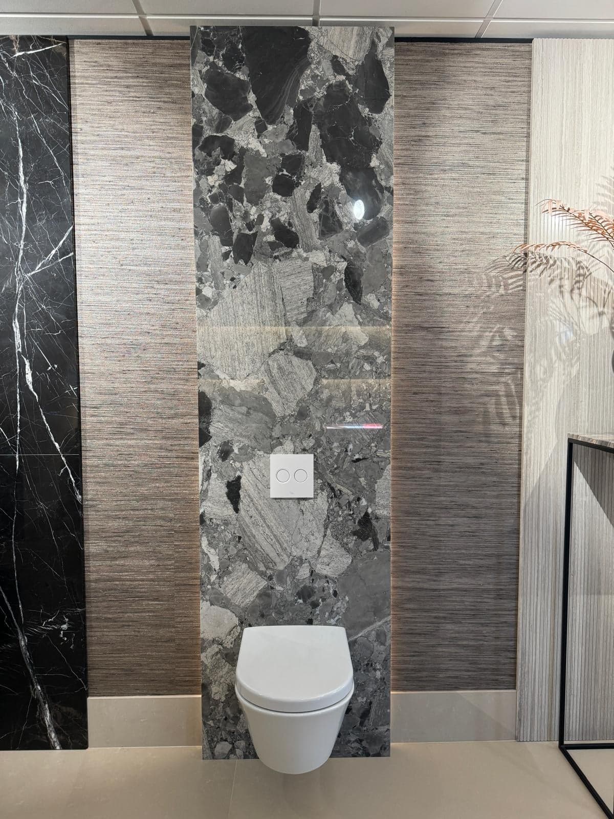 Zwevend toilet tegen een wand van grijs en zwart natuursteen in een natuursteen-showroom in Tilburg