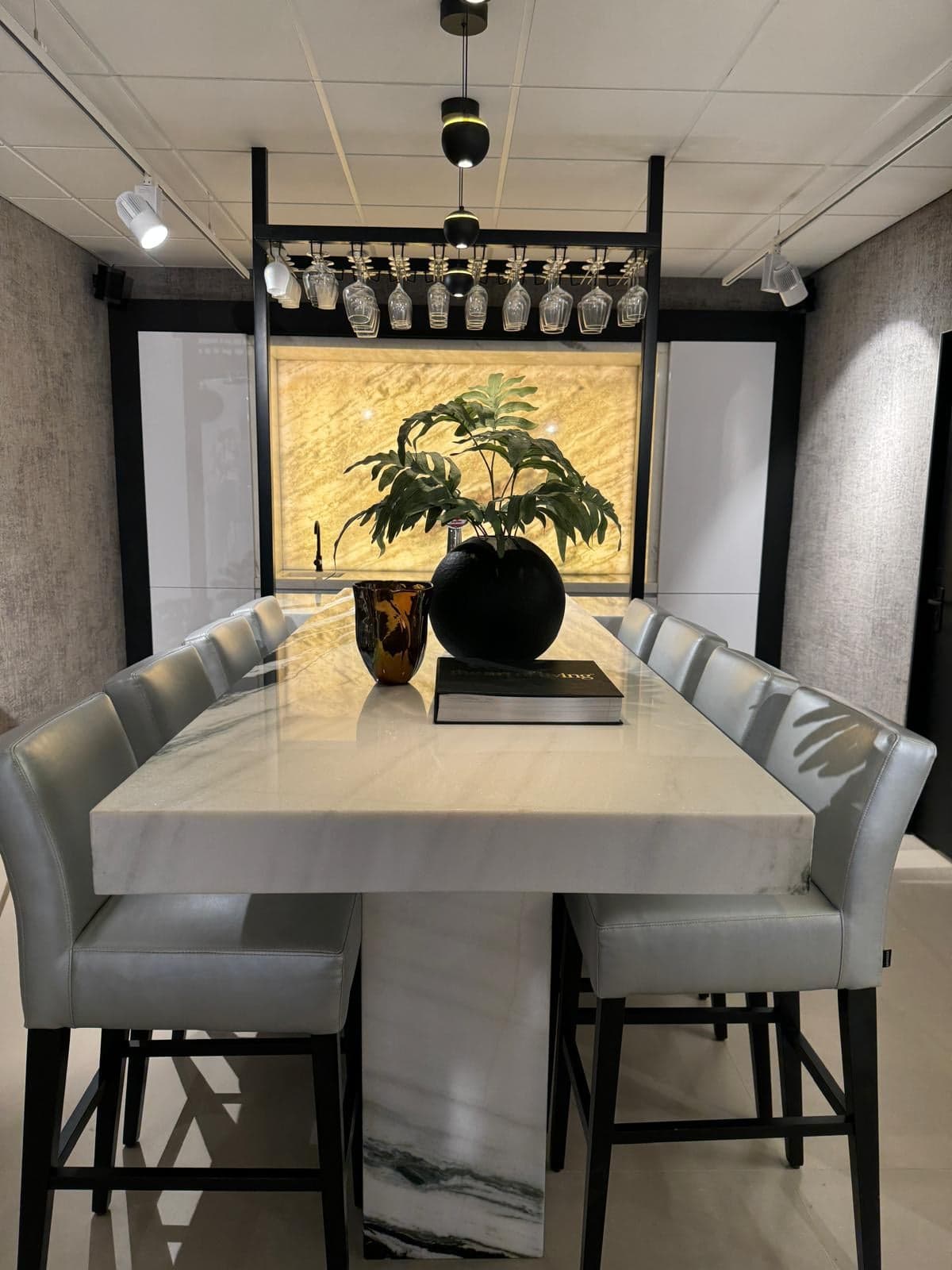Hoge tafel van wit natuursteen met barkrukken en een wijnrek in een natuursteen-showroom in Tilburg