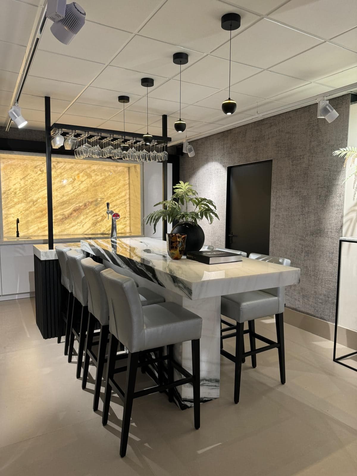 Bar van wit natuursteen met barkrukken en een tapkraan in een natuursteen-showroom in Tilburg