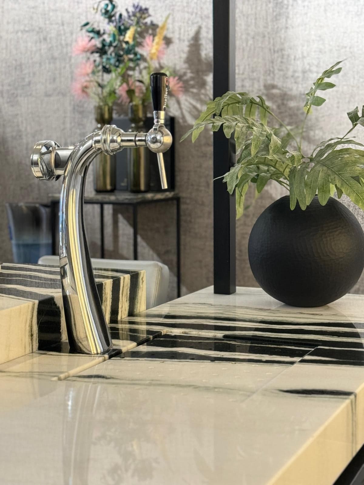 Gouden tapkraan bij een spoelbak van geaderd natuursteen in een natuursteen-showroom in Tilburg