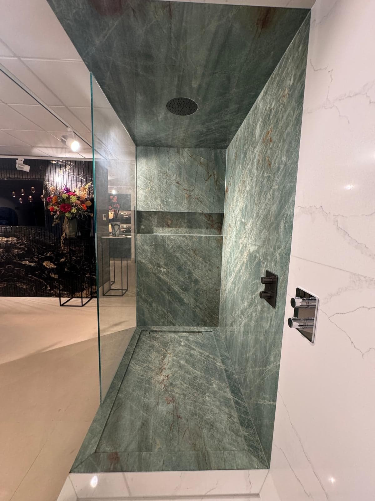 Inloopdouche bekleed met groen geaderd natuursteen in een natuursteen-showroom in Tilburg