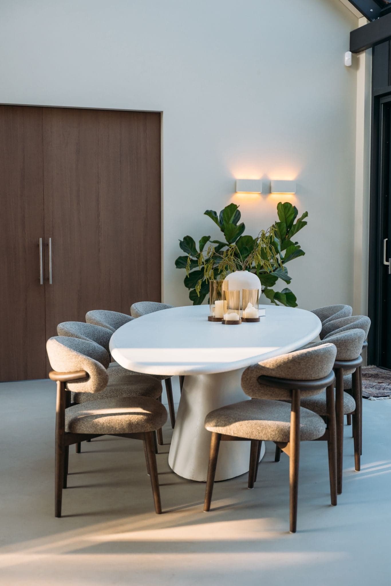 Ovale witte eettafel met zacht beklede eetstoelen en een houten kast in een villa in Sint-Oedenrode