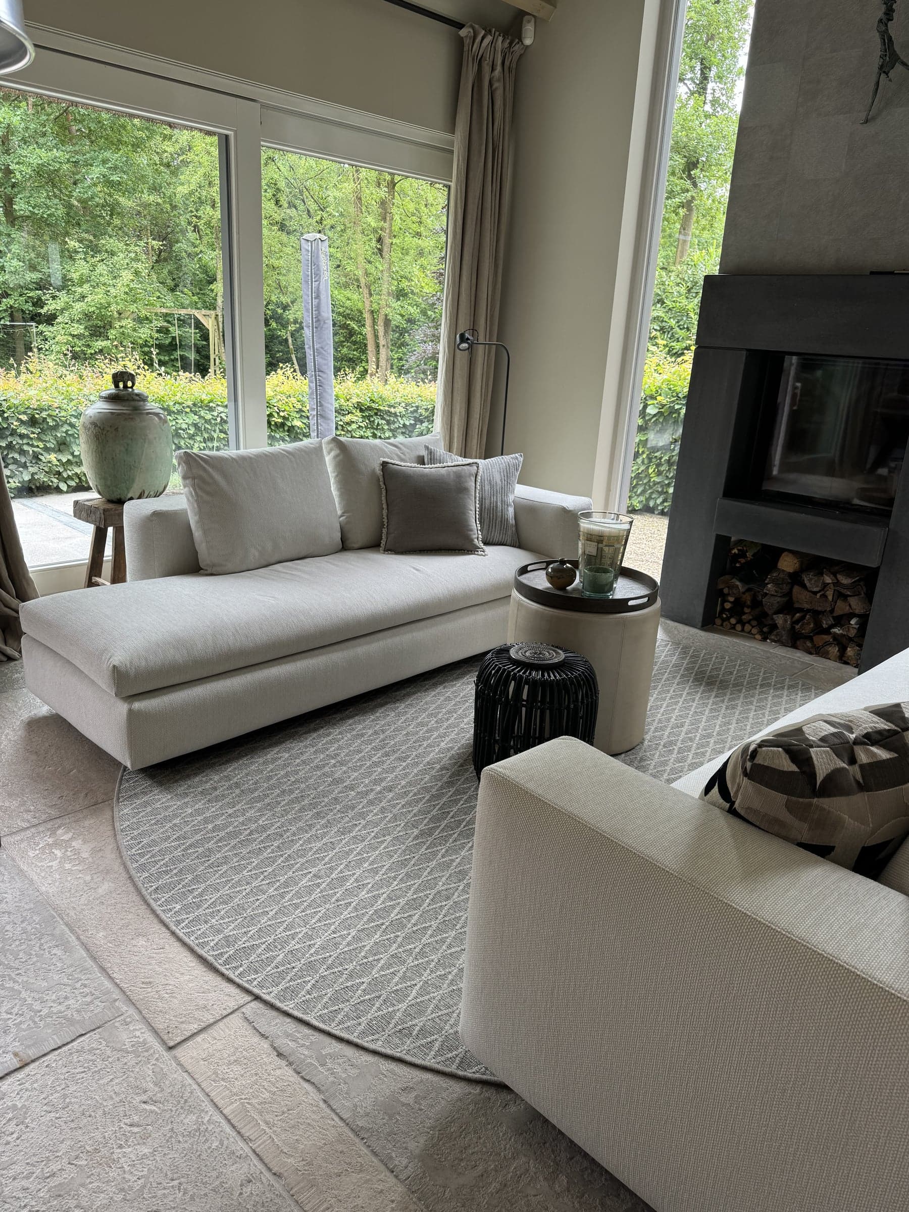 Woonkamer met witte bank, groene keramiek en doorkijk naar de tuin in een villa in Waalre
