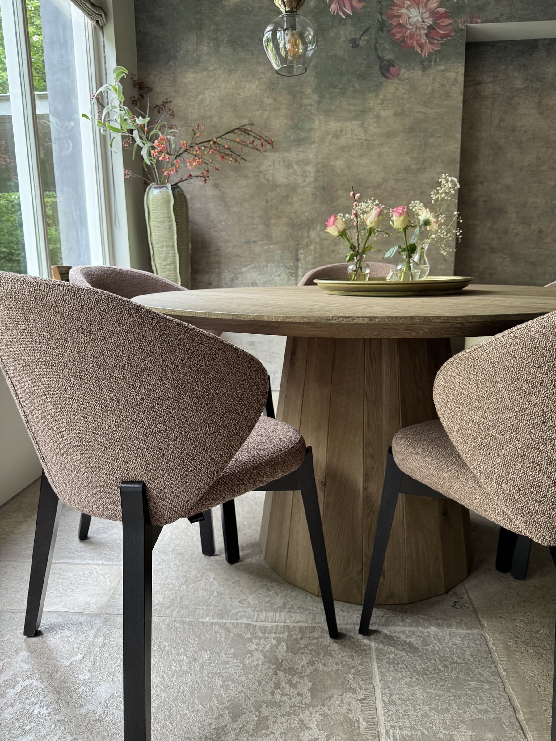 Ronde eikenhouten eettafel met zacht beklede eetstoelen en sfeervol behang in een villa in Waalre